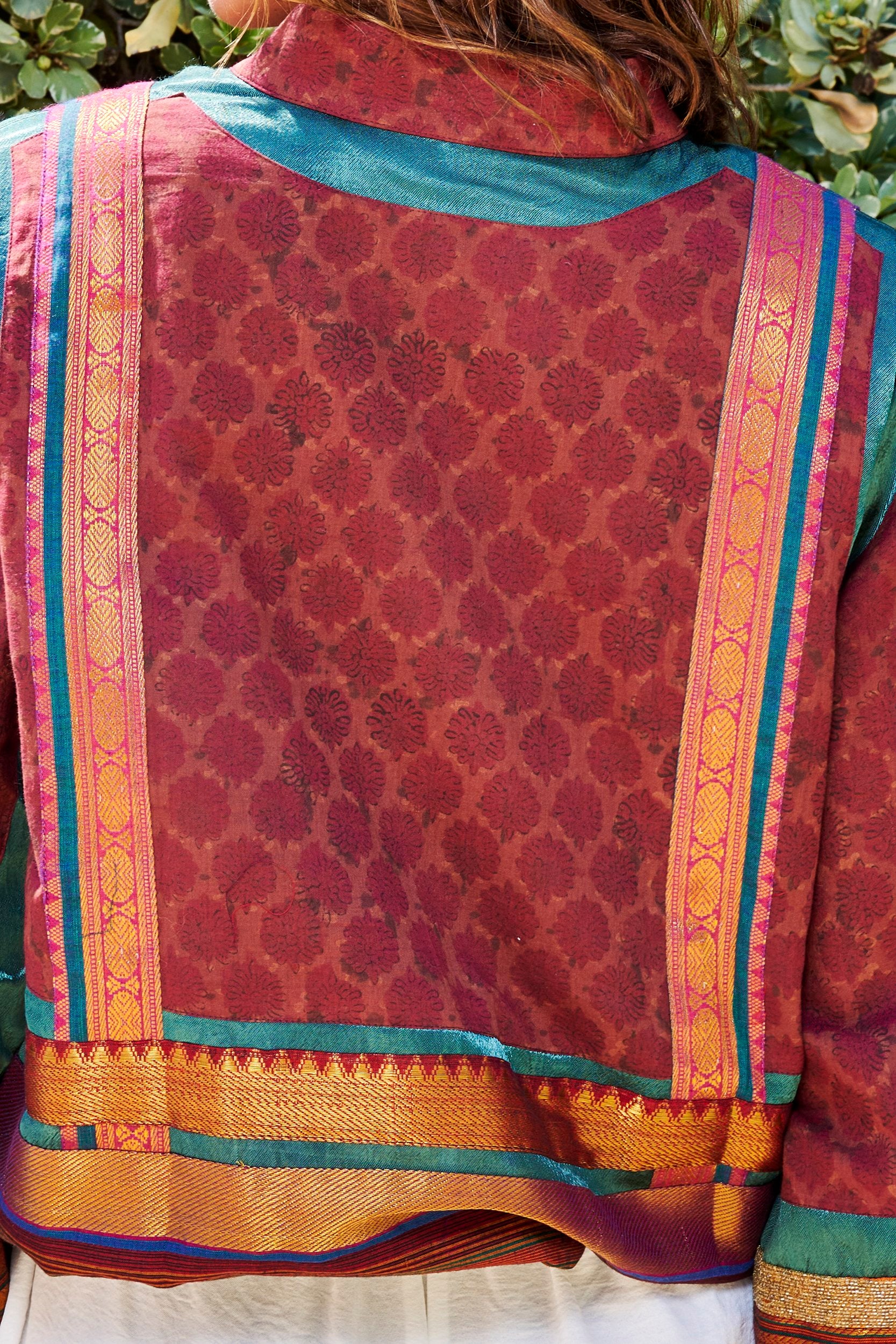 Closeup shot of a bomber jacket back showing hand block print design and gold weave border.