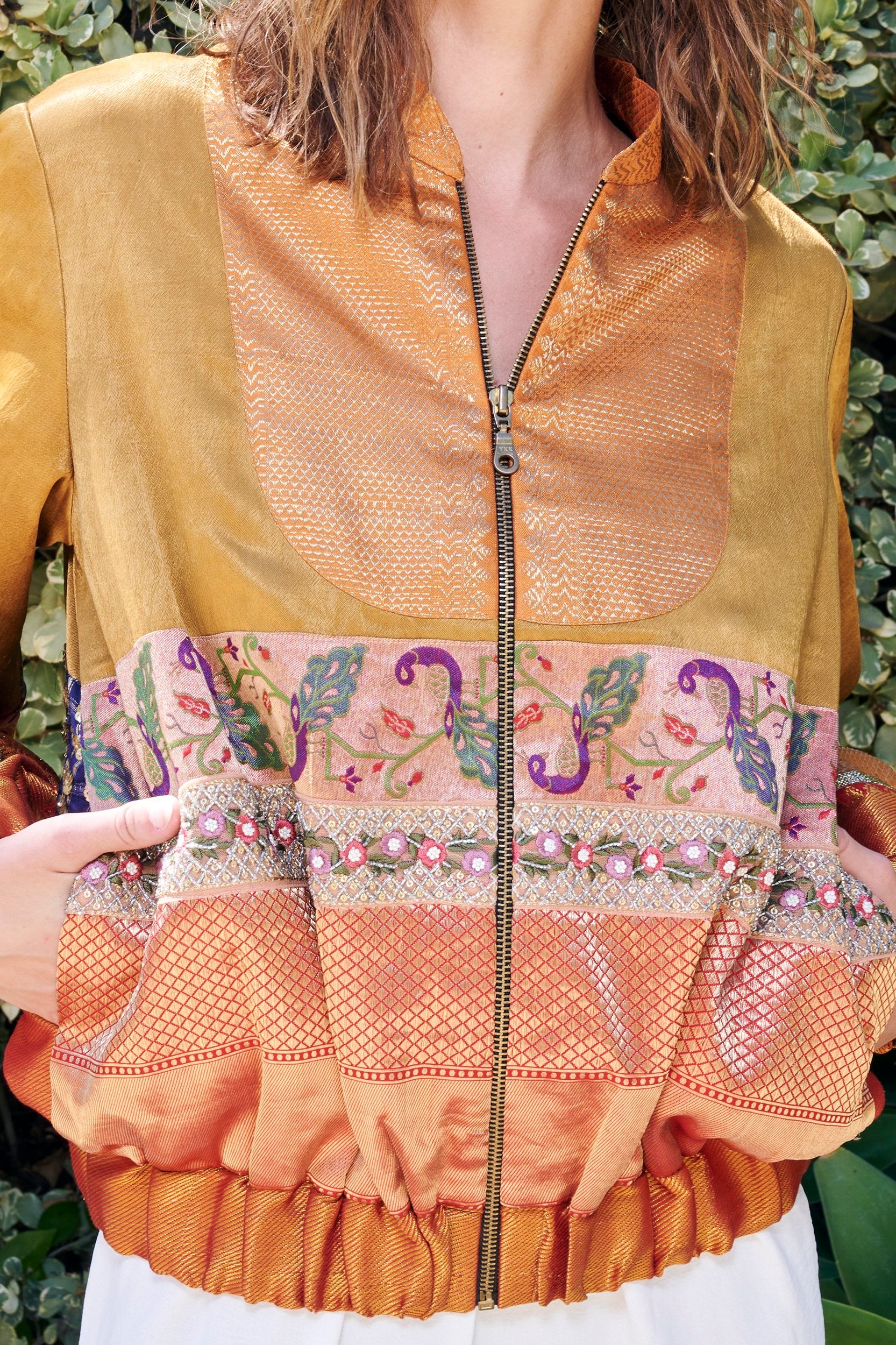 Closeup of a women's bomber jacket with peacock embroidered border. 