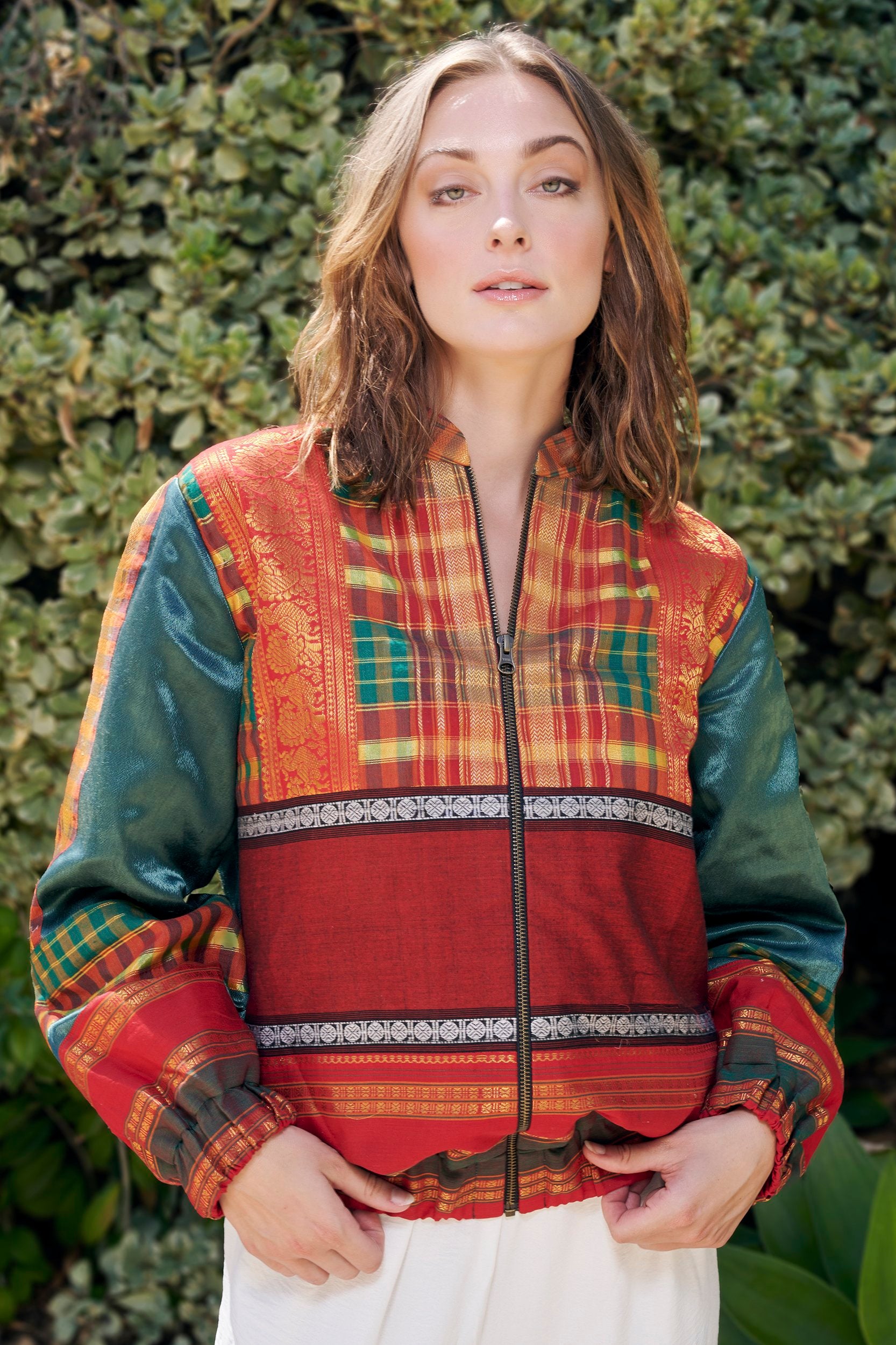 Model wearing a handmade bomber jacket made from repurposed precious fabric remnants.