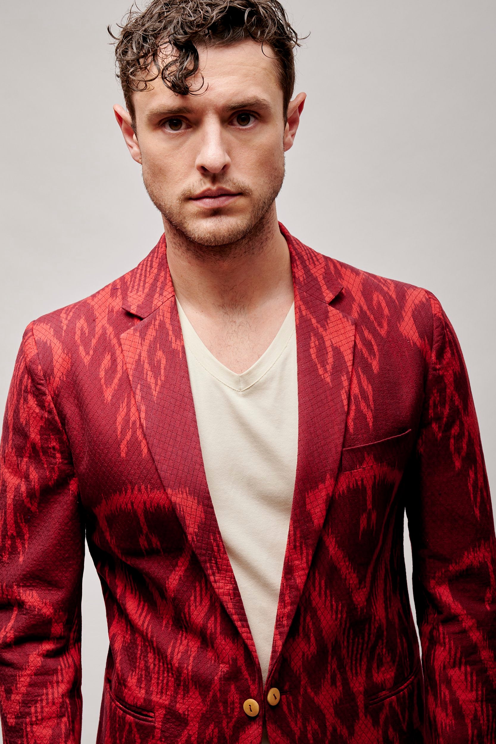 Model wearing a crimson blazer with a bold pattern. Hand woven and hand stitched.