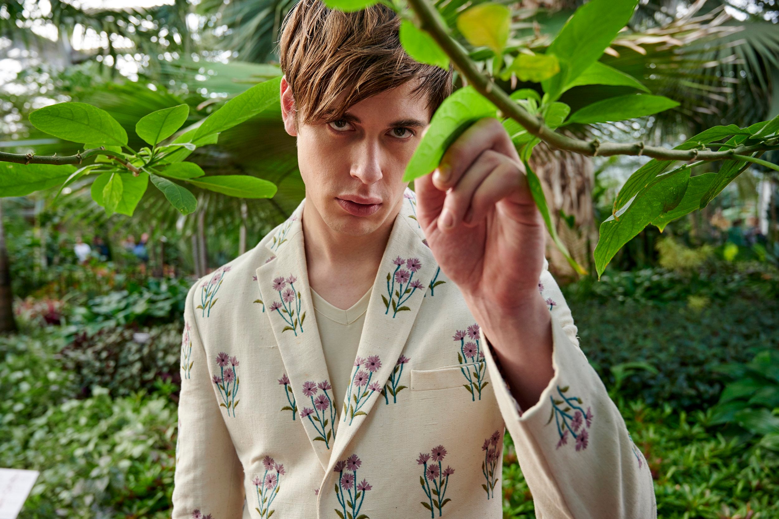 A model wearing an off-white embroidered blazer made with Undyed yarn. Beautifully hand-stitched and embellished with carved wooden buttons.