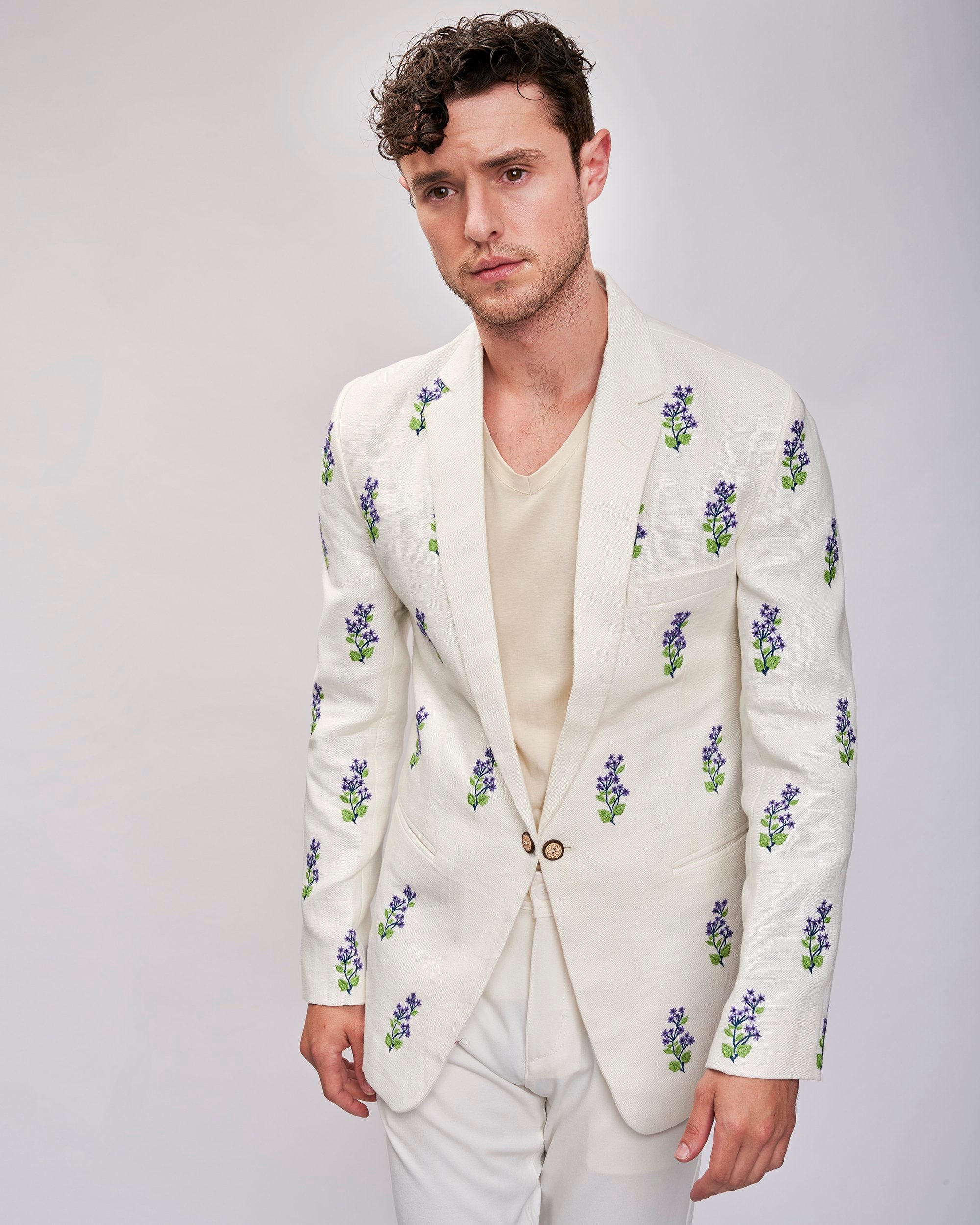 A model wearing an off-white embroidered lavender blazer made with Undyed yarn. Beautifully hand-stitched and embellished with carved wooden buttons.