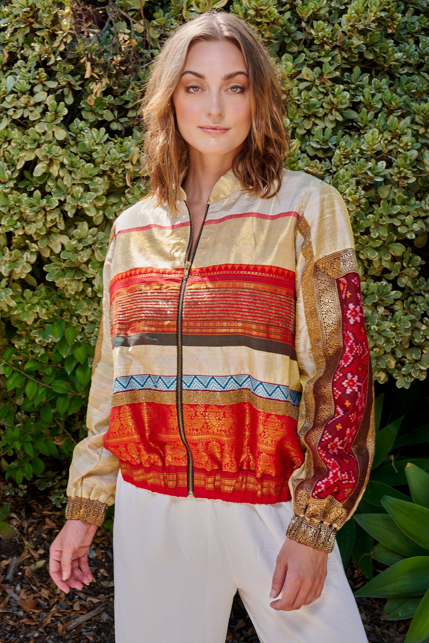 Model wearing a women's bomber jacket with patches. Made from repurposed fabric.