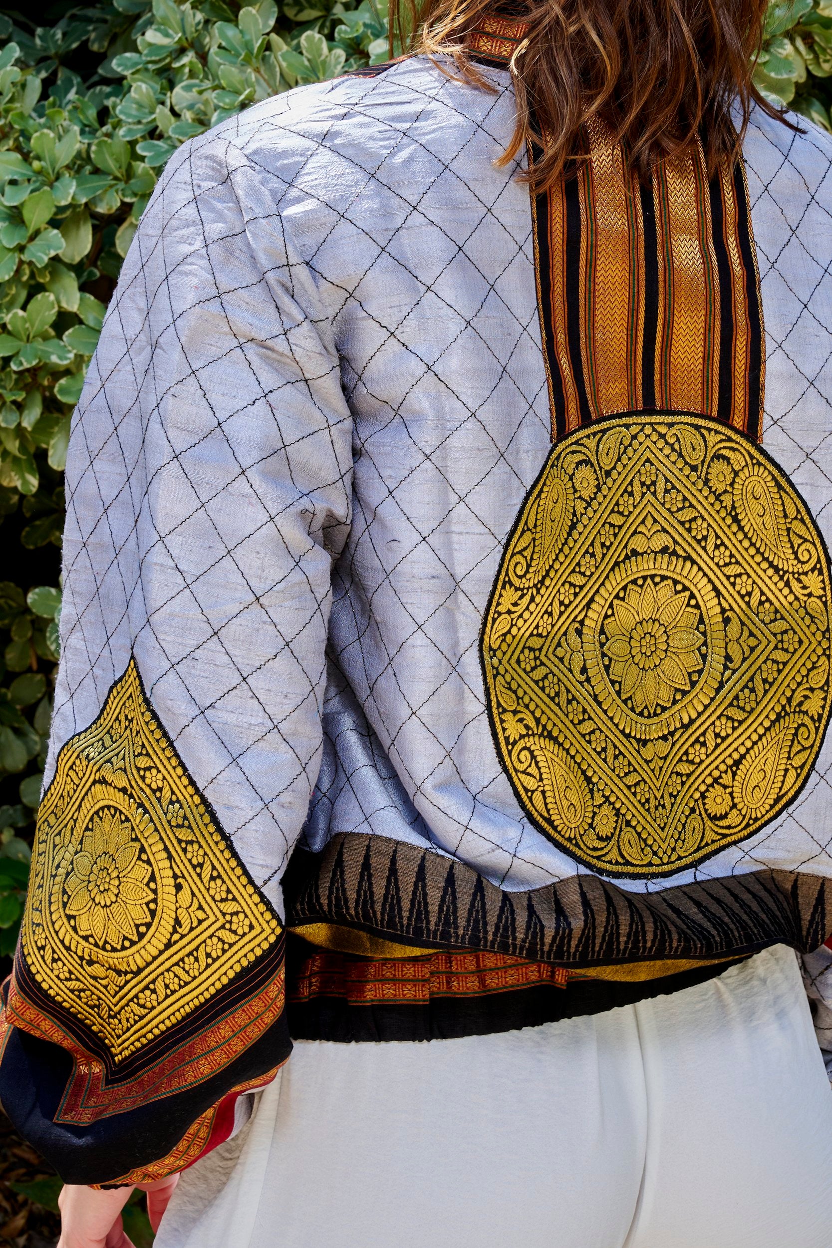 Women wearing a gray bomber jacket with a large round gold embroidered patch.