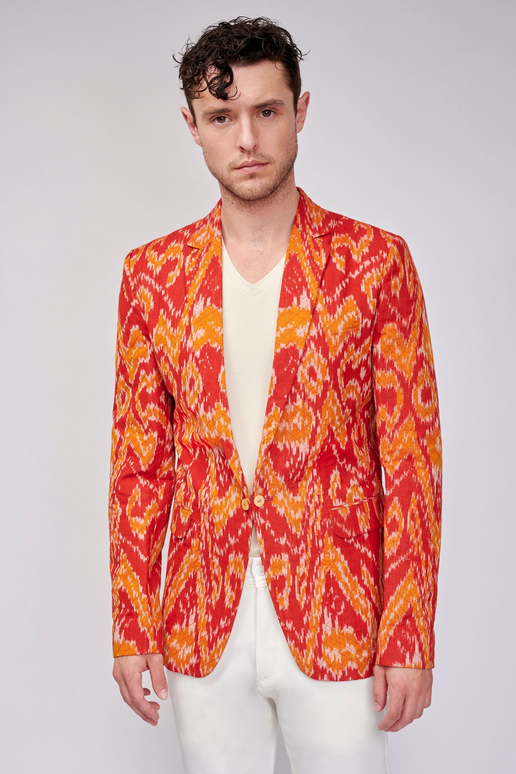 Model wearing a vermilion orange sports coat. It is woven in shades of a sunset. 