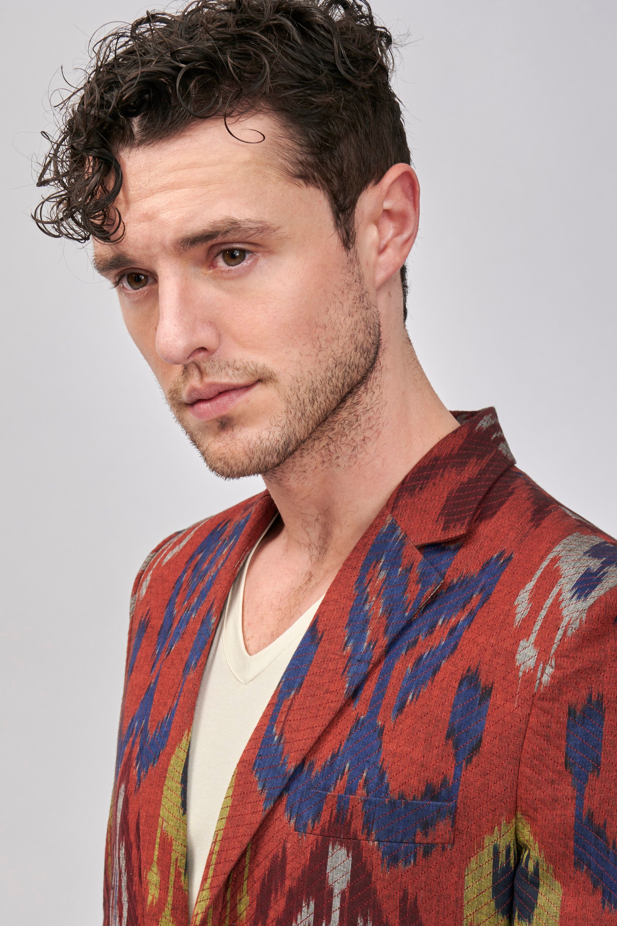Man wearing a brick-red Ikat blazer with a bold pattern. It is hand-woven  and hand stitched. 