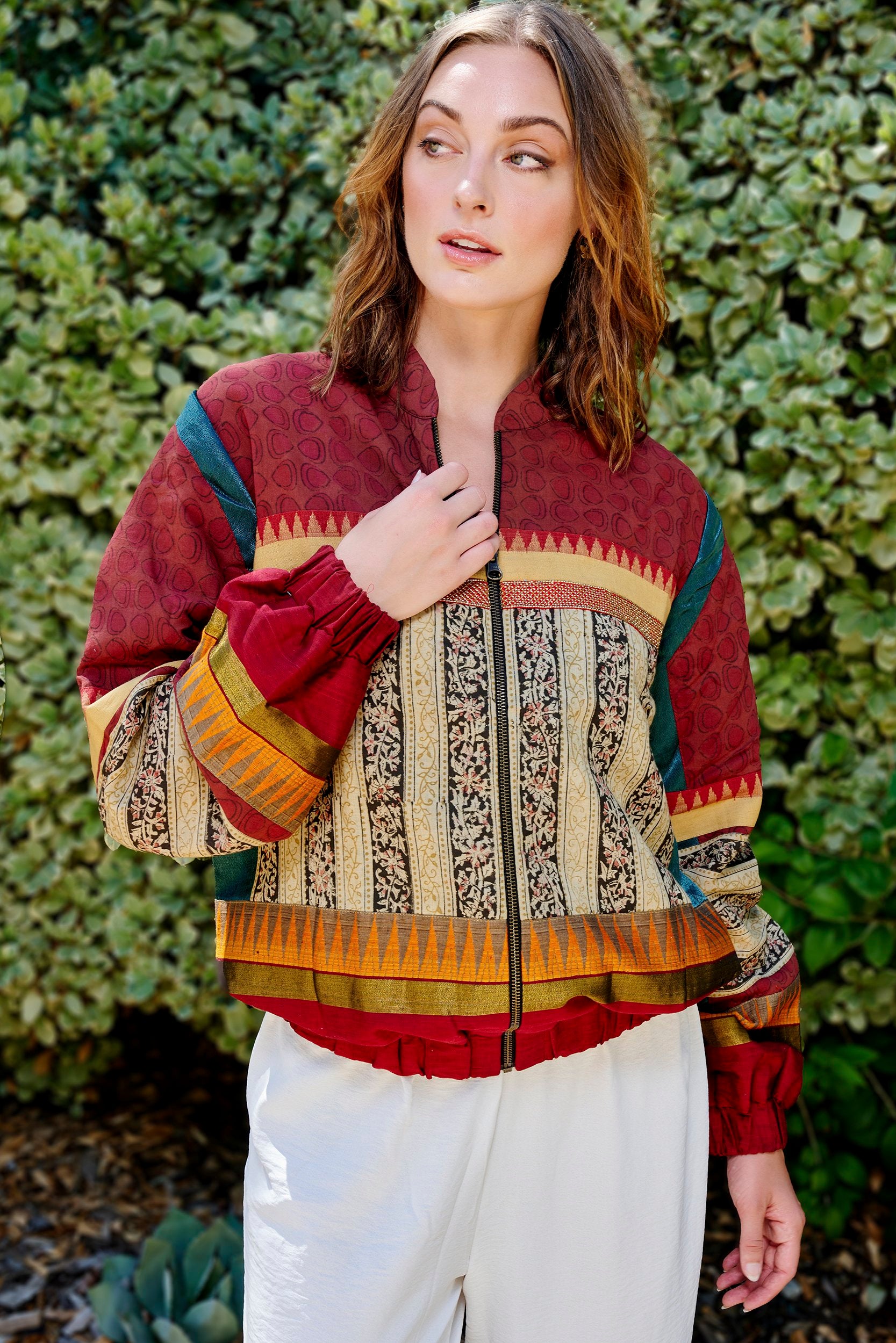 Model wearing a handmade bomber jacket in wine red color. It is hand block printed with floral strip patterns.