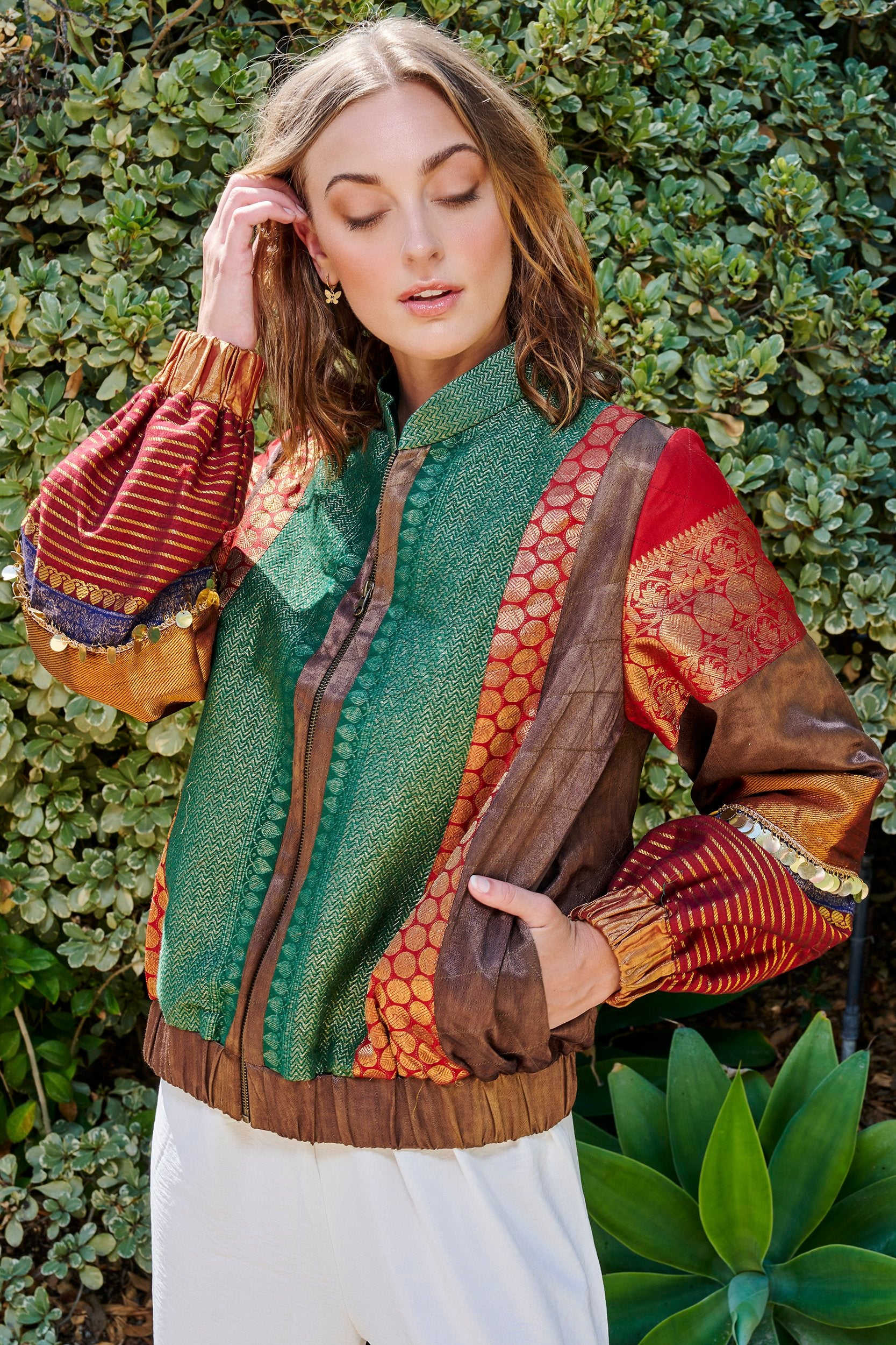 Model wearing a bold bomber jacket with gold embellishments on the sleeves.