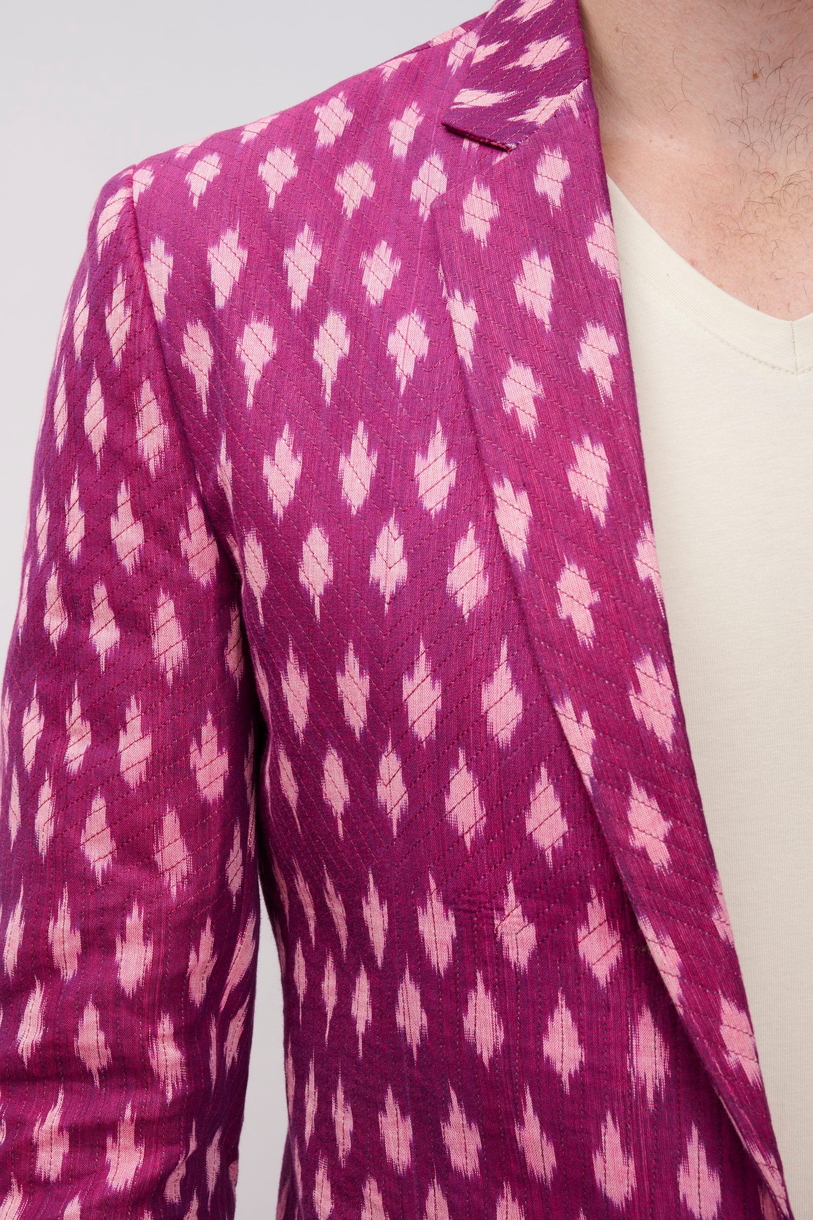 Closeup of a magenta color ikat blazer with cross stitch lines on the surface for added dimension.