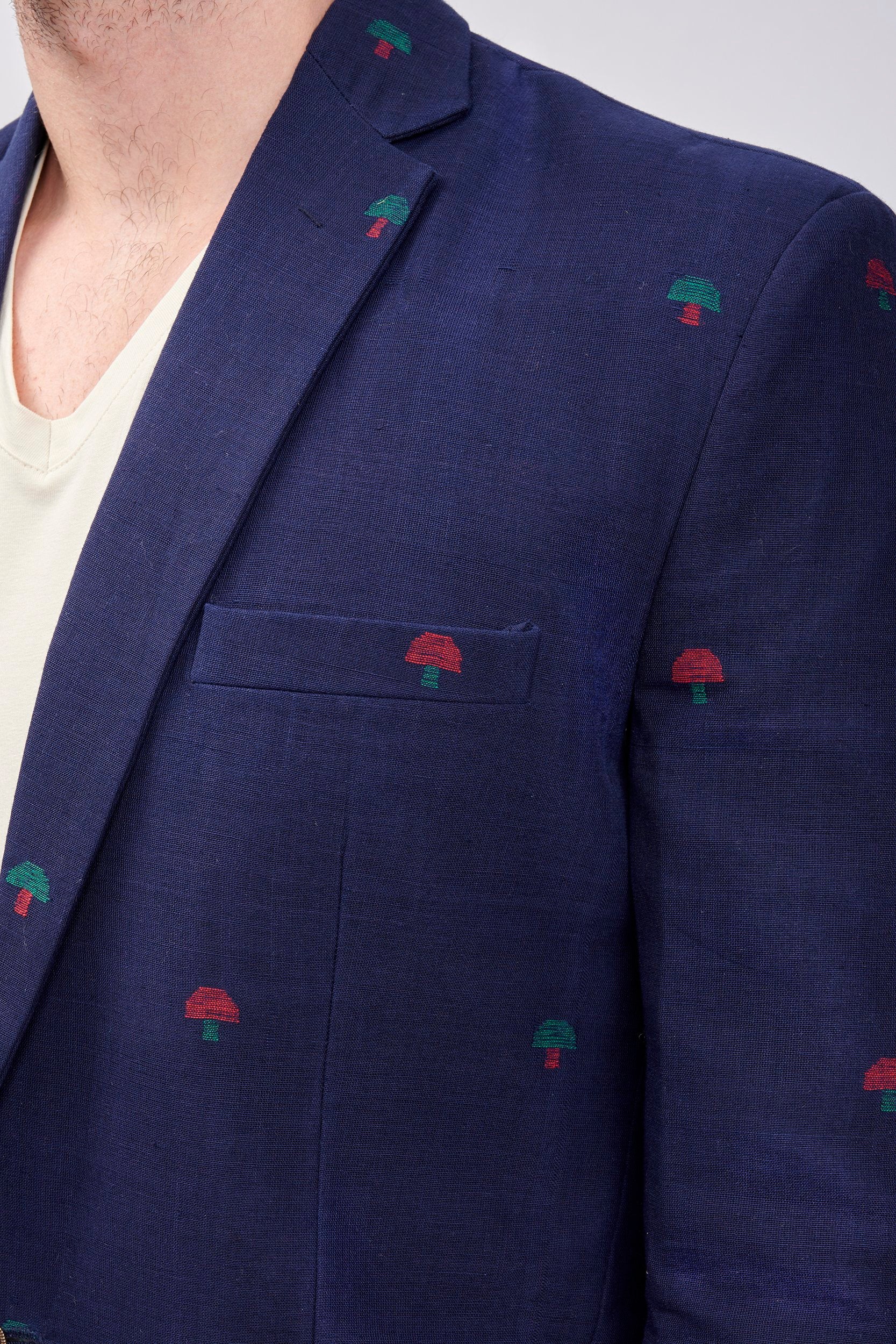 Closeup of a navy blue blazer with hand embroidered motifs on the surface.