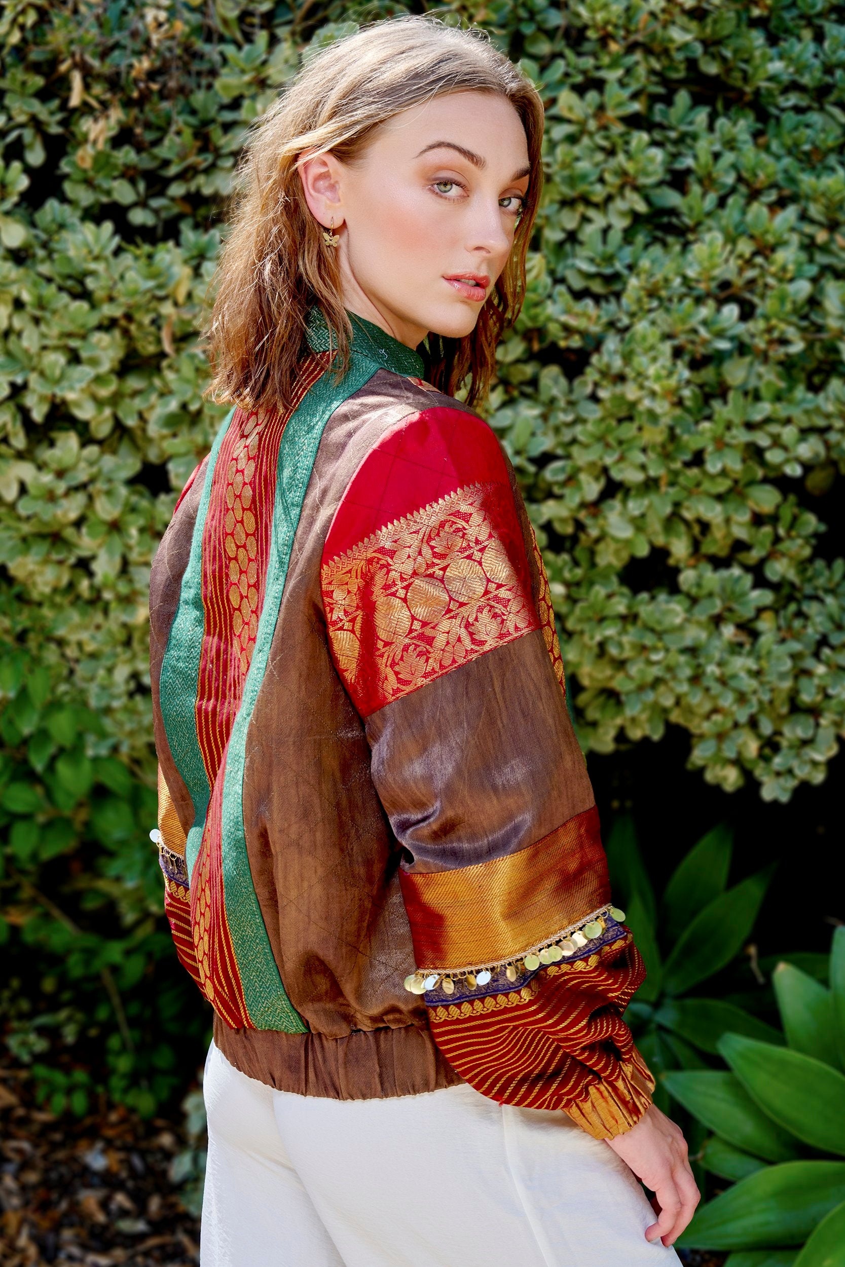 Model wearing a bold red and green bomber jacket with gold embellishments on the sleeves.