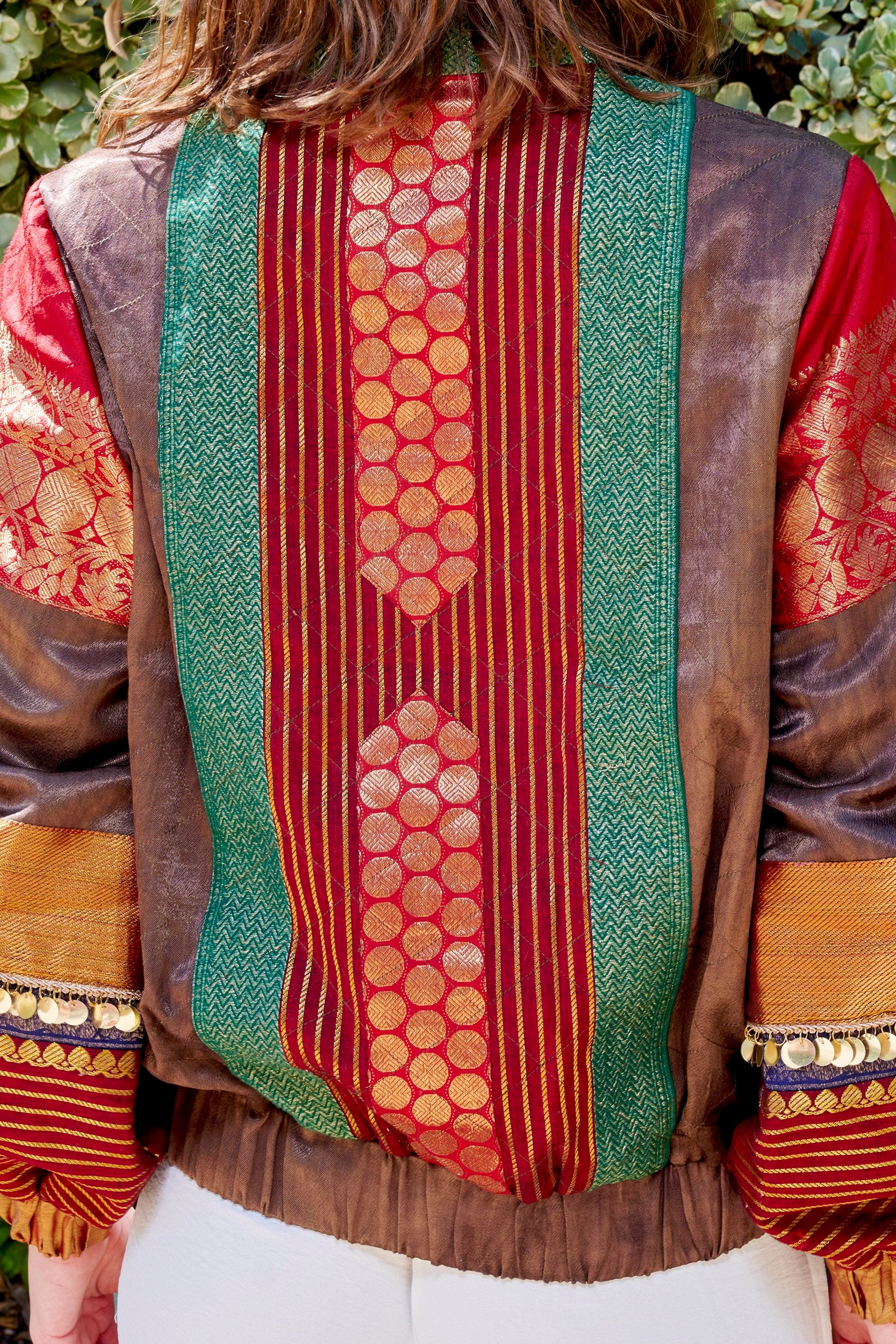 Closeup shot showcasing back of a green and red color jacket with gold embroidered patches.