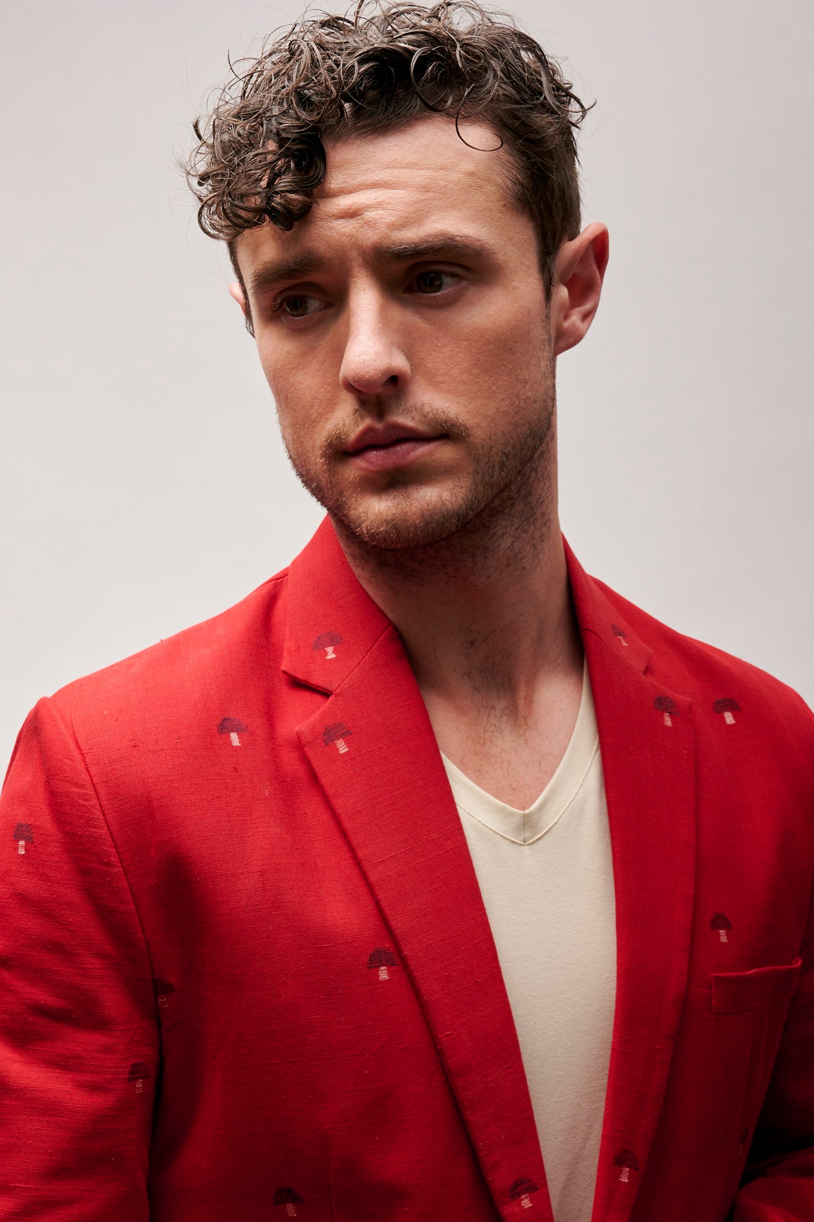 Model wearing a red cotton blazer with hand embroidered  small motifs.