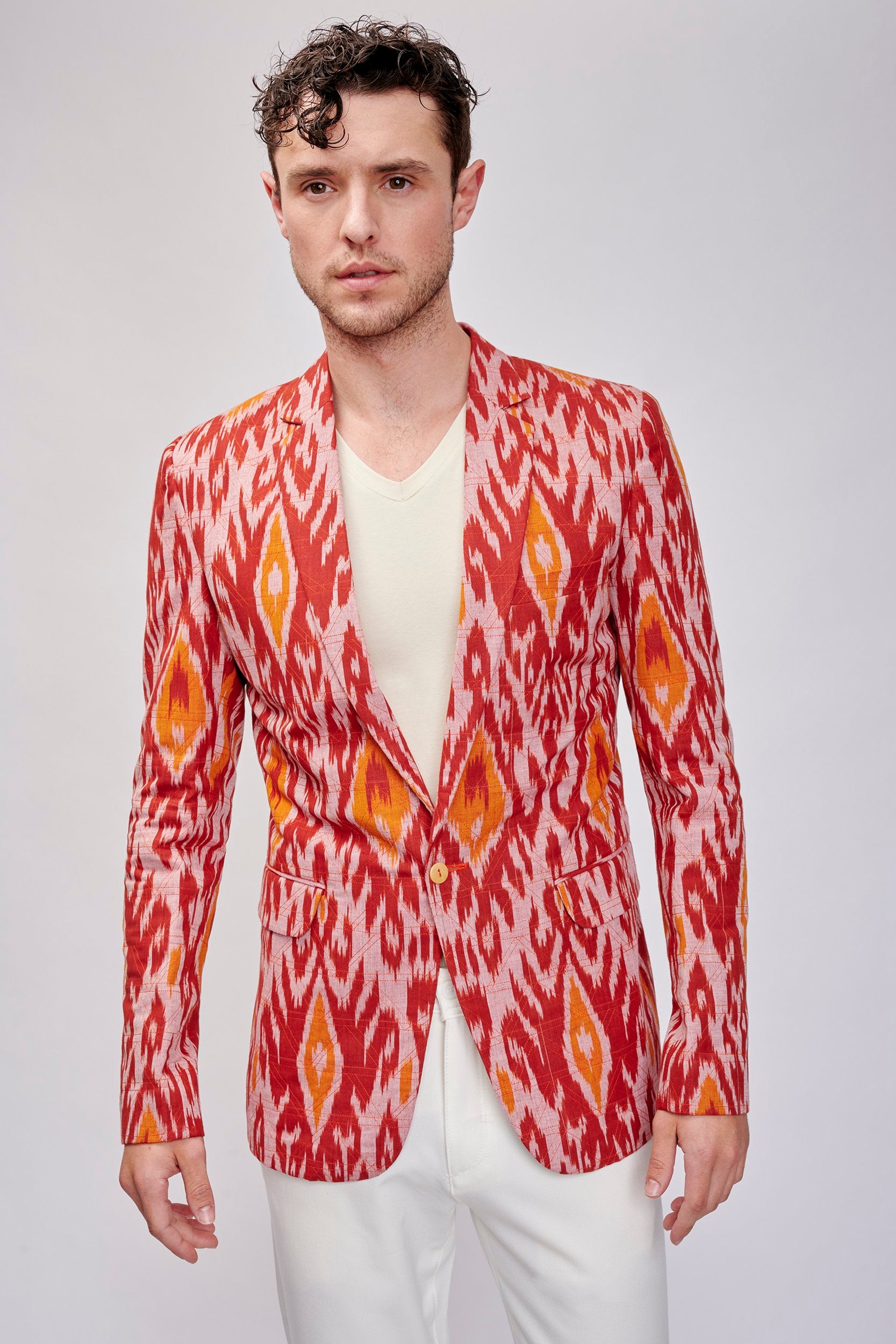 Model wearing a coral blazer with bright contrast hues, hand stitched and using sustainable materials.
