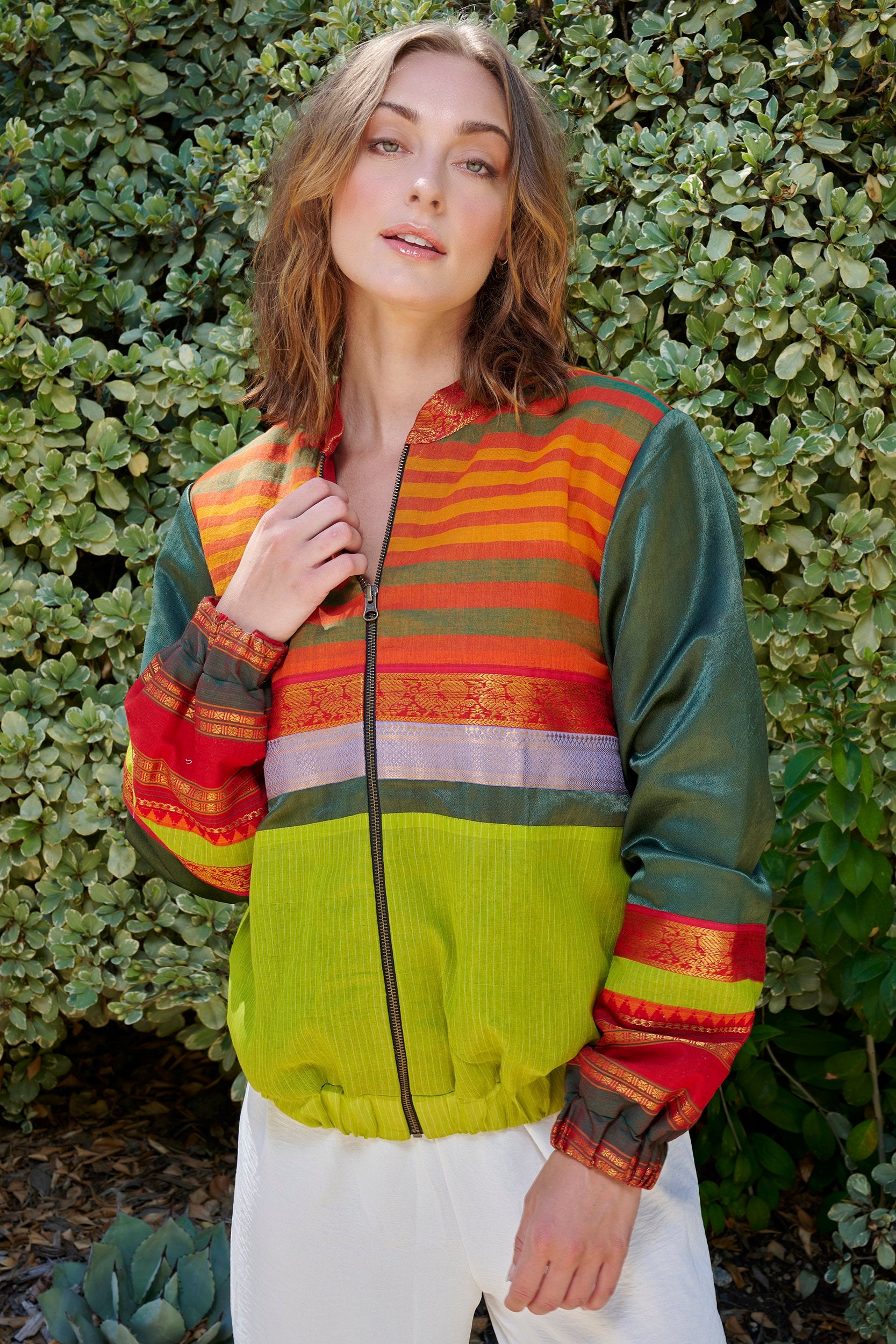 Model wearing a designer bomber jacket in green and orange color combination.