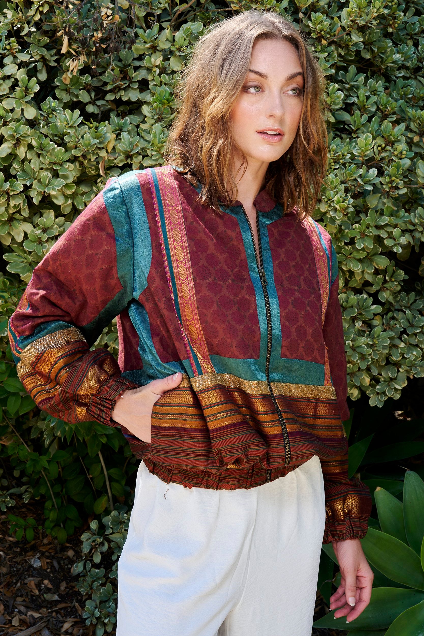 Model wearing a wine red bomber jacket with teal blue accent. Handmade from repurposed precious fabric remnants.