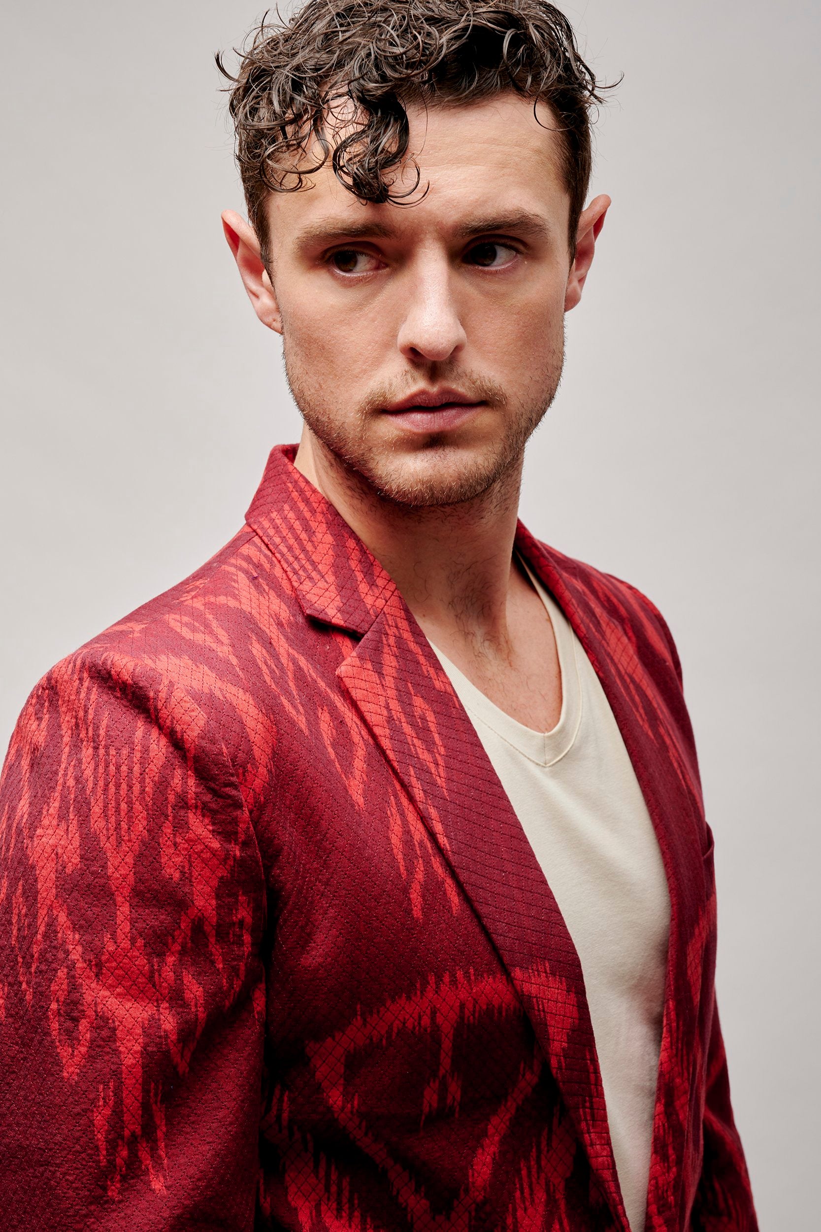 Model wearing a crimson jacket with a bold pattern. Hand woven and hand stitched.