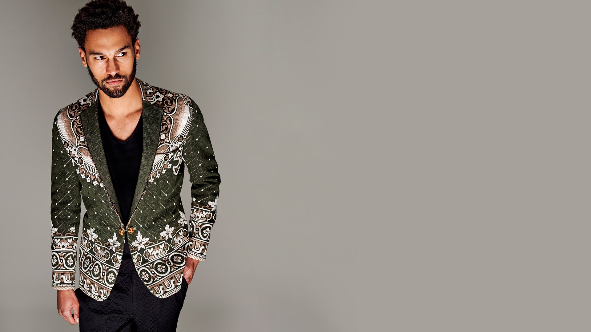 A model wearing a sustainable jacquard jacket in green and ivory colors.